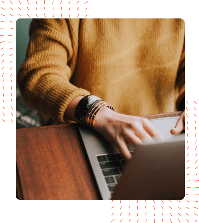 Close-up of a person in a mustard yellow sweater typing on a laptop, adorned with stylish silver bracelets.