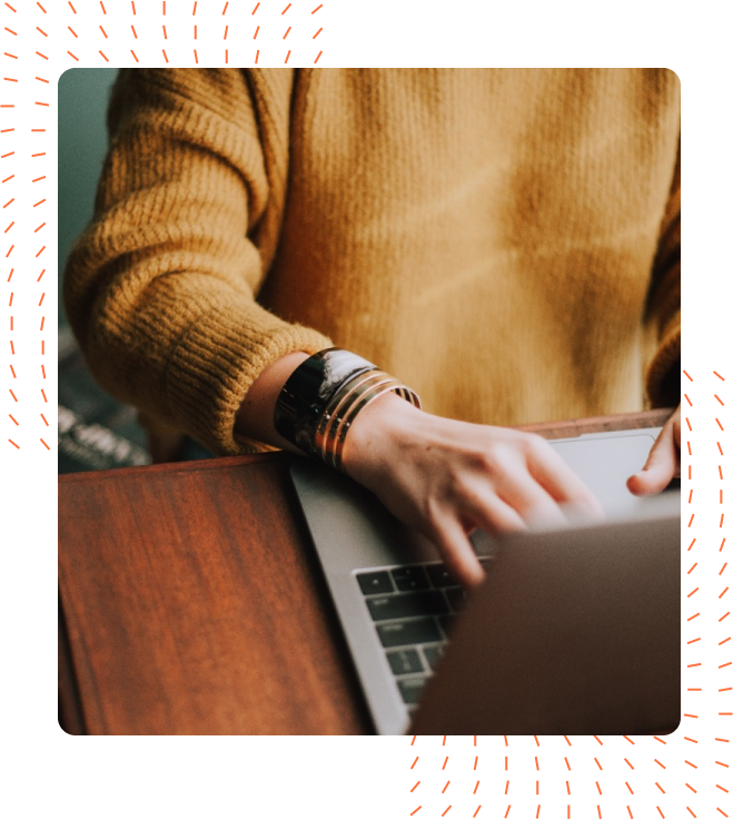 Close-up of a person in a mustard yellow sweater typing on a laptop, adorned with stylish silver bracelets.